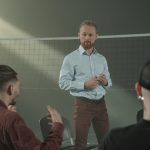 Four people engaged in a group discussion inside a room with a net background.